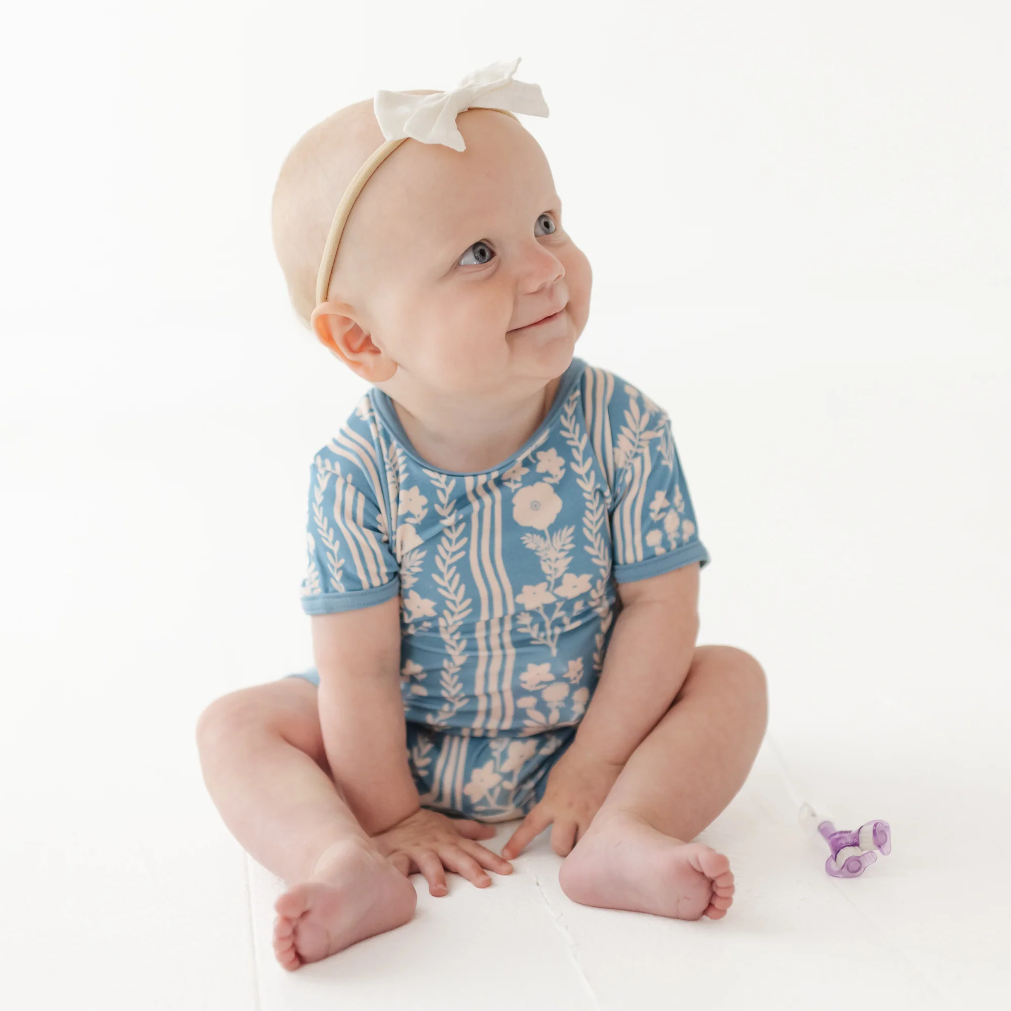 Baby wears blue and white patterned romper